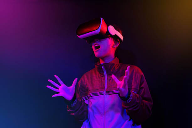 teenager with virtual reality glasses on a blue and red colored background. - 电竞 個照片及圖片檔